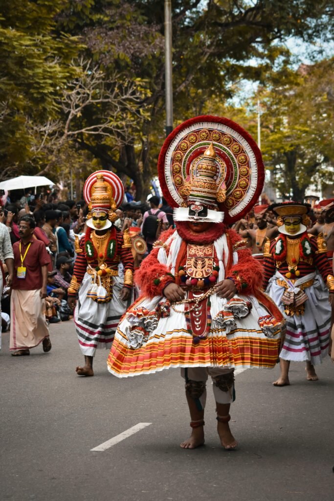 Traditional Theyyam performers in vibrant costumes during a cultural procession in Kerala, showcasing India’s rich ritual heritage | Immersive Trips
