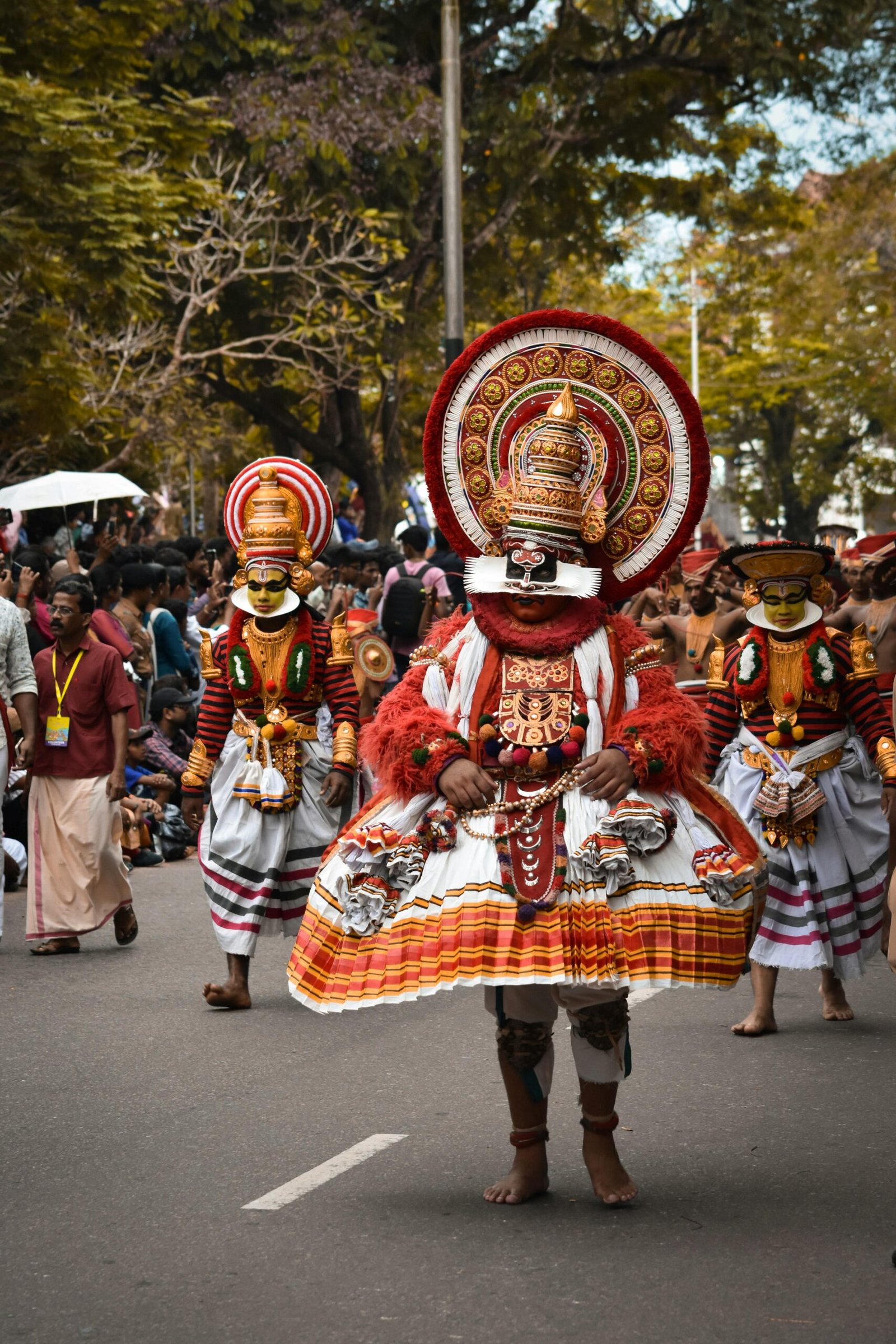 Traditional Theyyam performers in vibrant costumes during a cultural procession in Kerala, showcasing India’s rich ritual heritage | Immersive Trips
