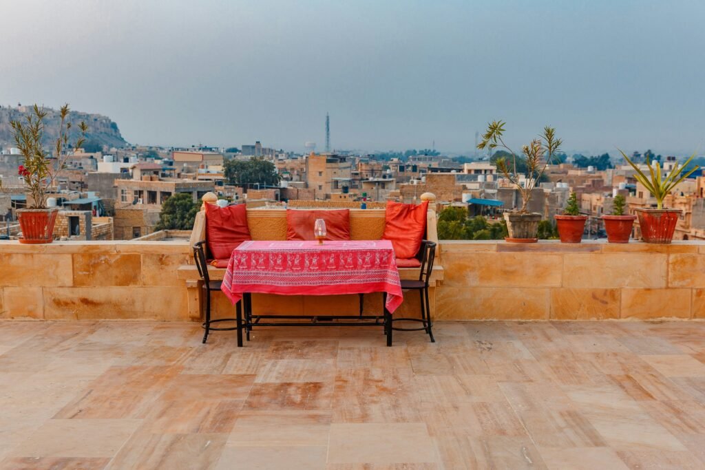 Hotel Lal Garh Fort And Palace in Jaisalmer, featuring a traditional stone bench decorated with red cushions and a red patterned tablecloth.
