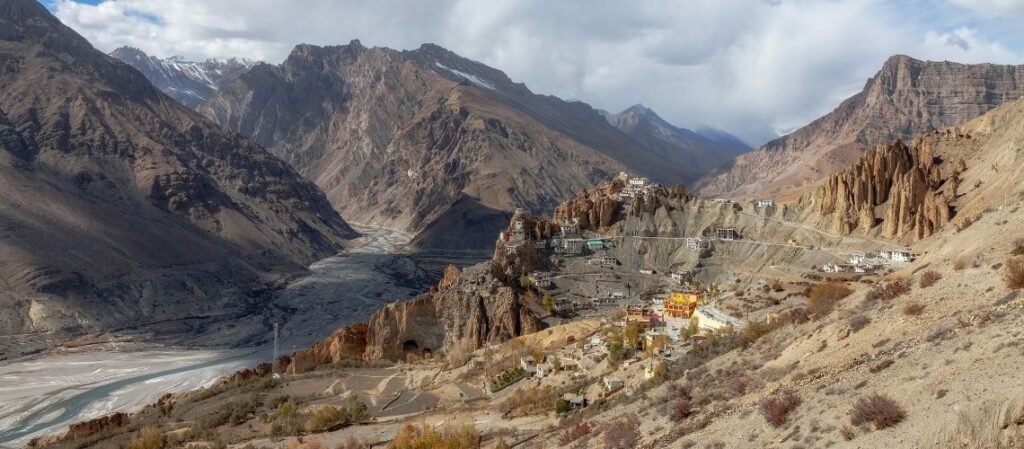 Dhankar Monastery village perched on a high cliff edge in the Spiti Valley of Himachal Pradesh, India, overlooking the wide valley and the distant winding river.