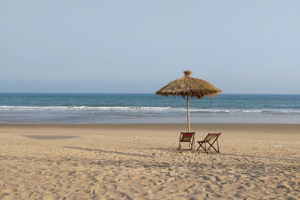 Couple and Honeymoon Tour Packages in Odisha 6 Couple and Honeymoon Tour Packages in Odisha | Two beach chairs under a thatched umbrella facing the sea in Odisha