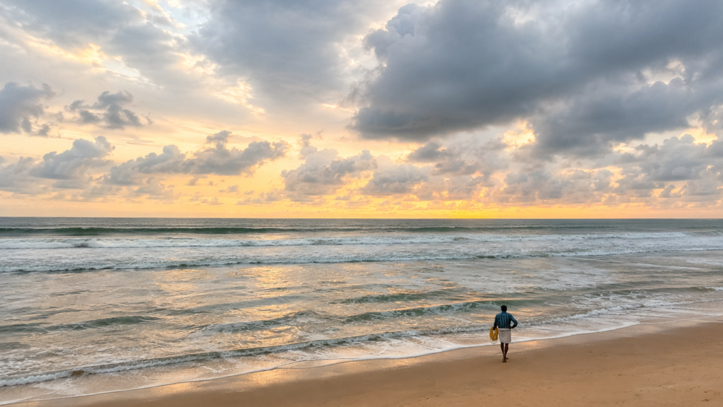 A man walking along Gopalpur Beach at sunrise