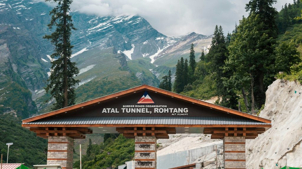 Entrance portal of the Atal Tunnel at 10,040 feet with snow-streaked mountains behind it near Manali